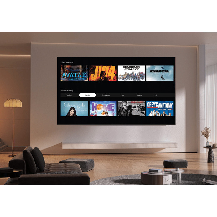 A Gaba GLV-8524W 85 hüvelykes tévé nappali falára szerelve, a képernyőn filmajánló csempék két sorban